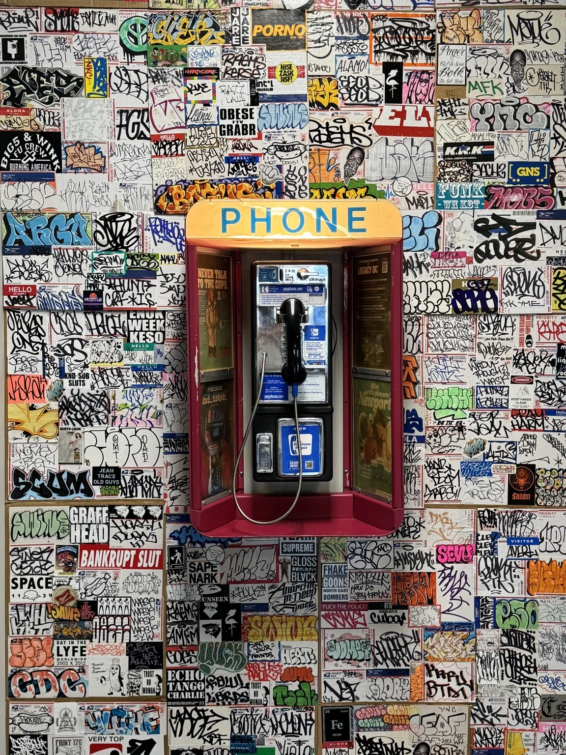 Vintage payphone mounted on a colorful graffiti-covered wall